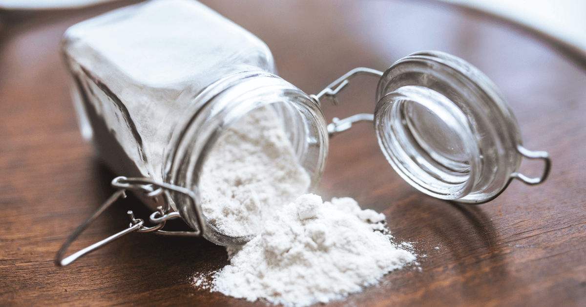 Baking Soda Use, a white powder, is stored in a glass jar on a wooden table.