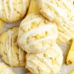 Close-up of Pineapple Cookies drizzled with white glaze, surrounded by fresh pineapple slices.