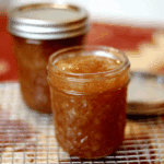 Glass jars filled with Homemade Spiced Honey Pear Jam cooling on a wire rack.