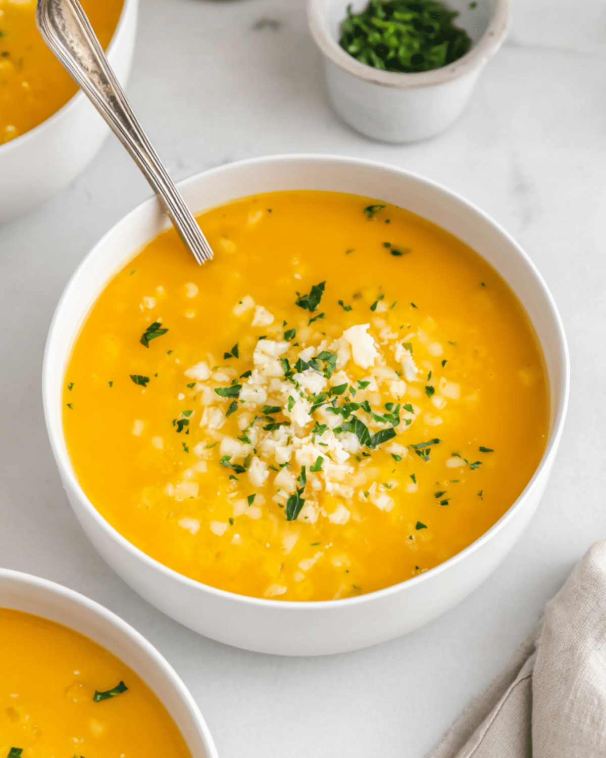 Italian Penicillin Soup in a white bowl, featuring a rich golden broth with rice, finely chopped herbs, and grated cheese on top.