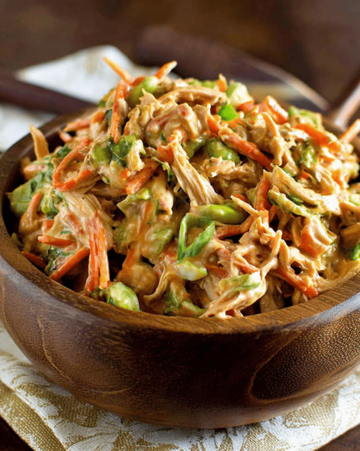 Wooden bowl filled with creamy Asian chicken salad made with shredded chicken, carrots, edamame, and cabbage.