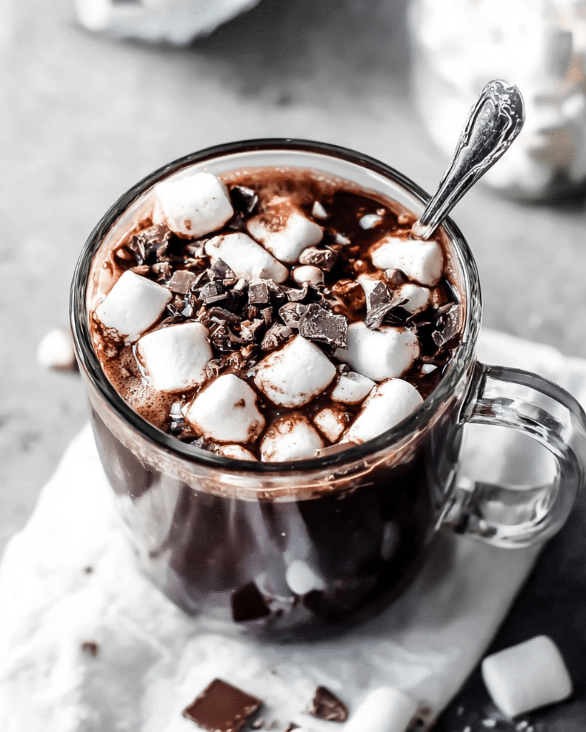 Glass mug filled with Dark Chocolate Hot Chocolate topped with mini marshmallows and chocolate shavings.