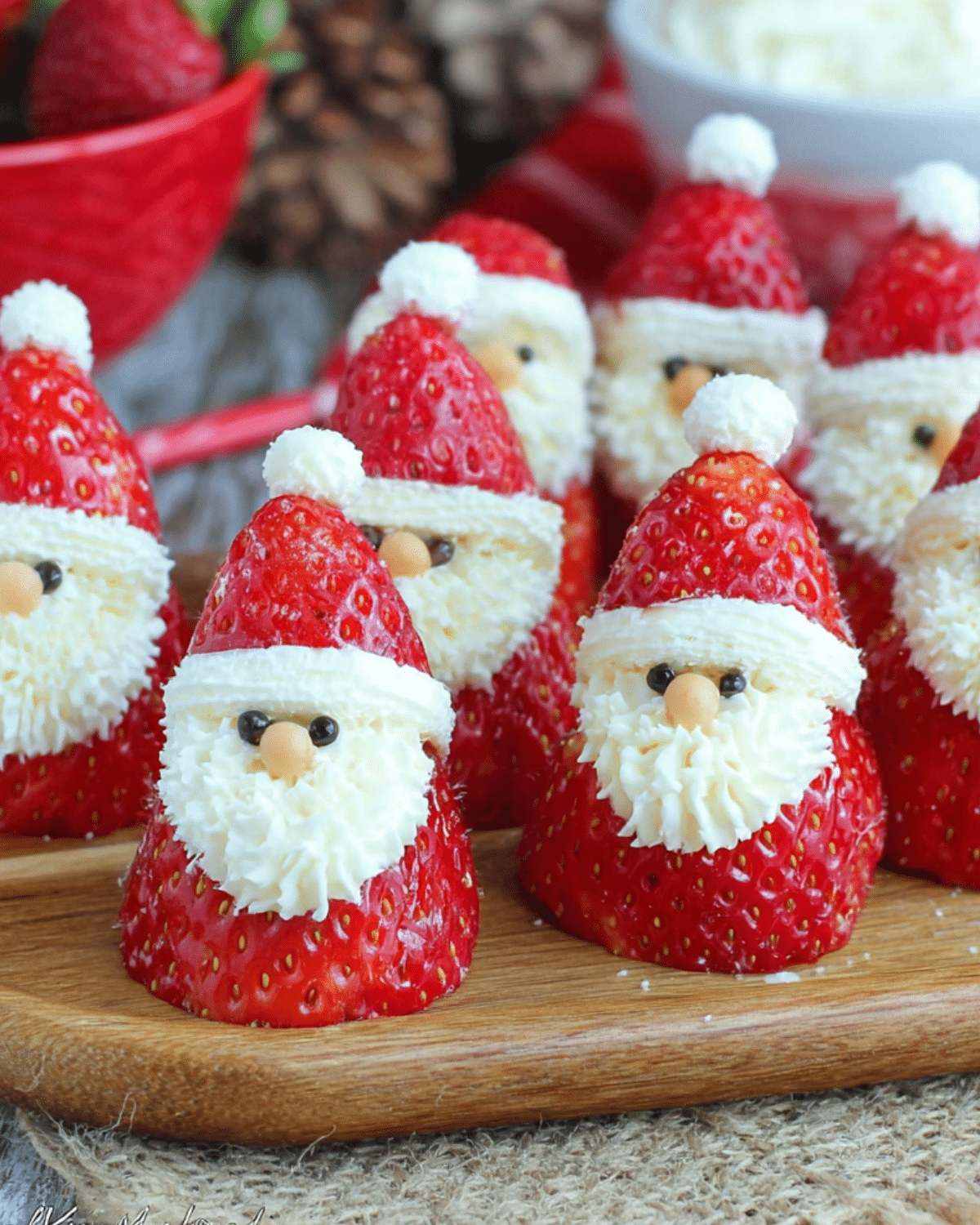 Mini strawberry Santas made with fresh strawberries, whipped cream, and chocolate chips for eyes.