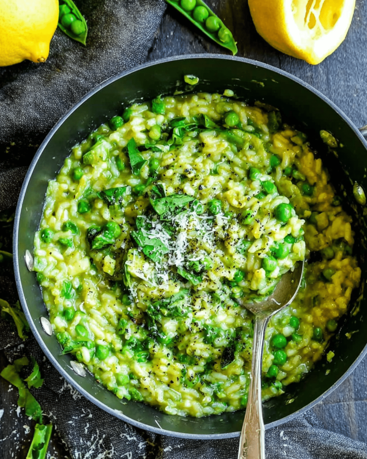 Spring Pea Risotto in a black skillet, garnished with grated parmesan, black pepper, and fresh herbs.