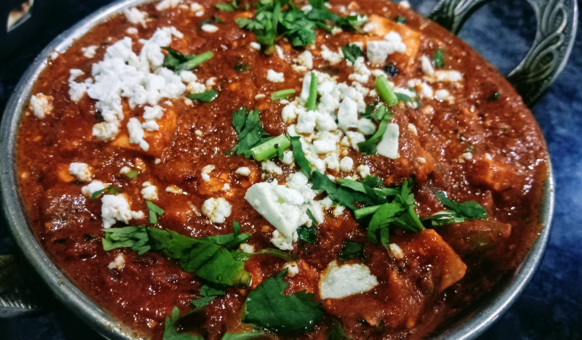 delicious Cheesy White Bean Tomato Bake. The dish features a golden brown, bubbly cheese topping over creamy white beans and tangy diced tomatoes, garnished with fresh basil leaves. It's presented in a ceramic dish on a rustic wooden table, highlighting its home-cooked, comforting appeal.