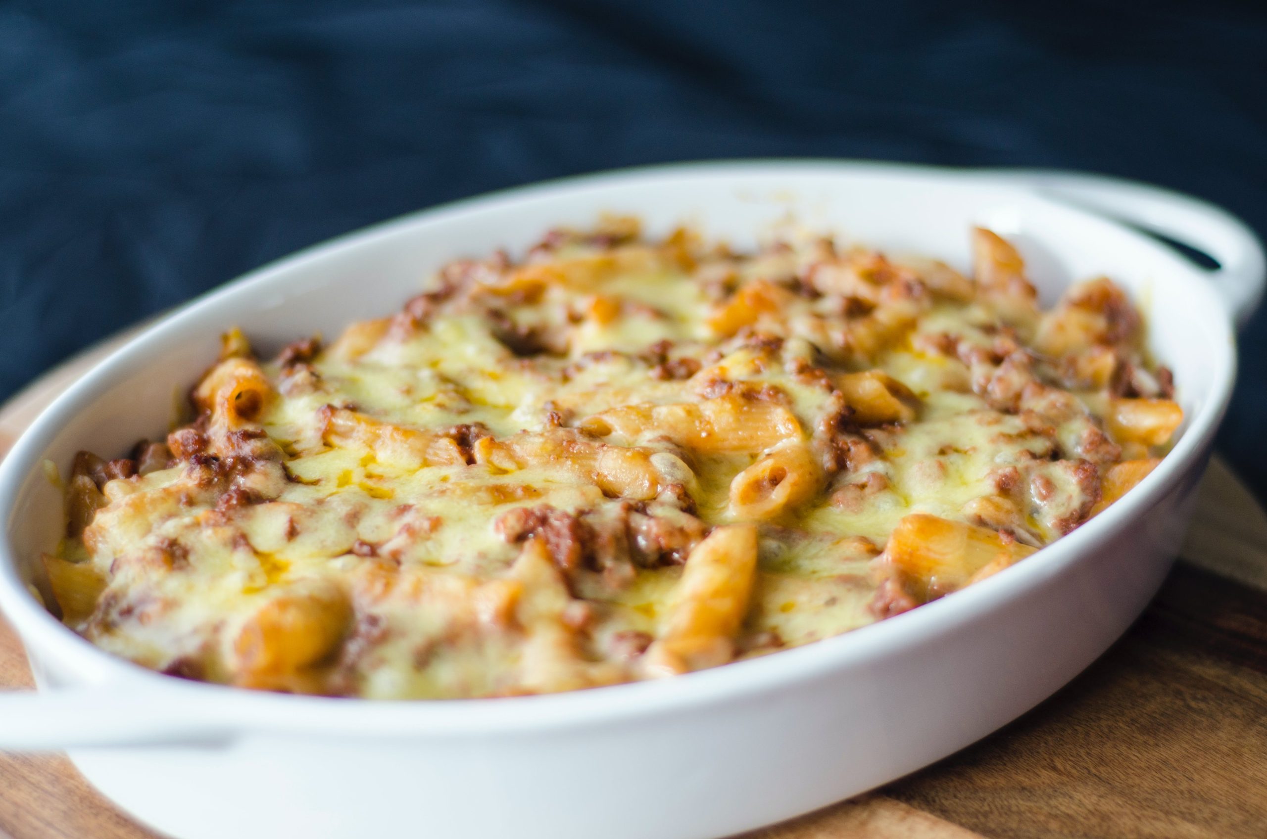 Close-up shot of freshly baked macaroni and cheese in a baking dish, showcasing a golden-brown, crispy cheese topping over creamy pasta