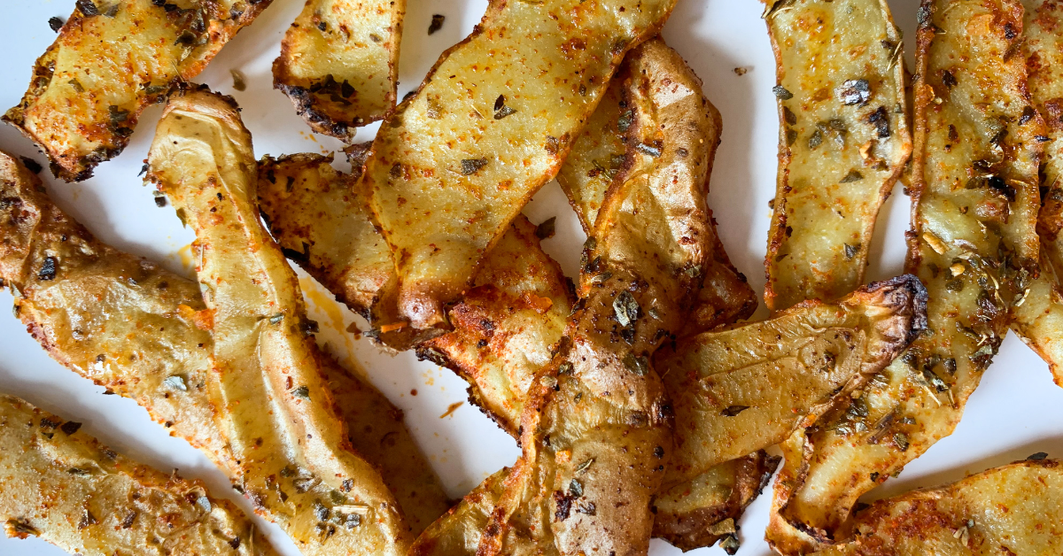 A plate of seasoned fries, with a sprinkle of seasoning, showcasing the crispy potato skin.