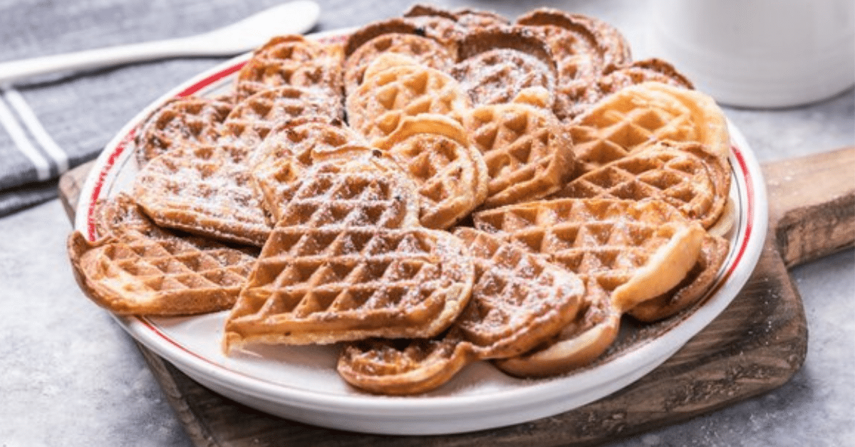 A plate of waffles topped with powdered sugar, creating a delightful and sweet breakfast treat.
