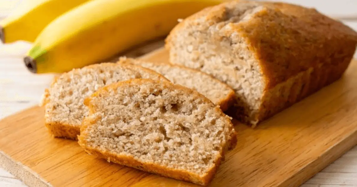 A loaf of banana breadBaking without baking soda on a cutting board, ready to be sliced and enjoyed.