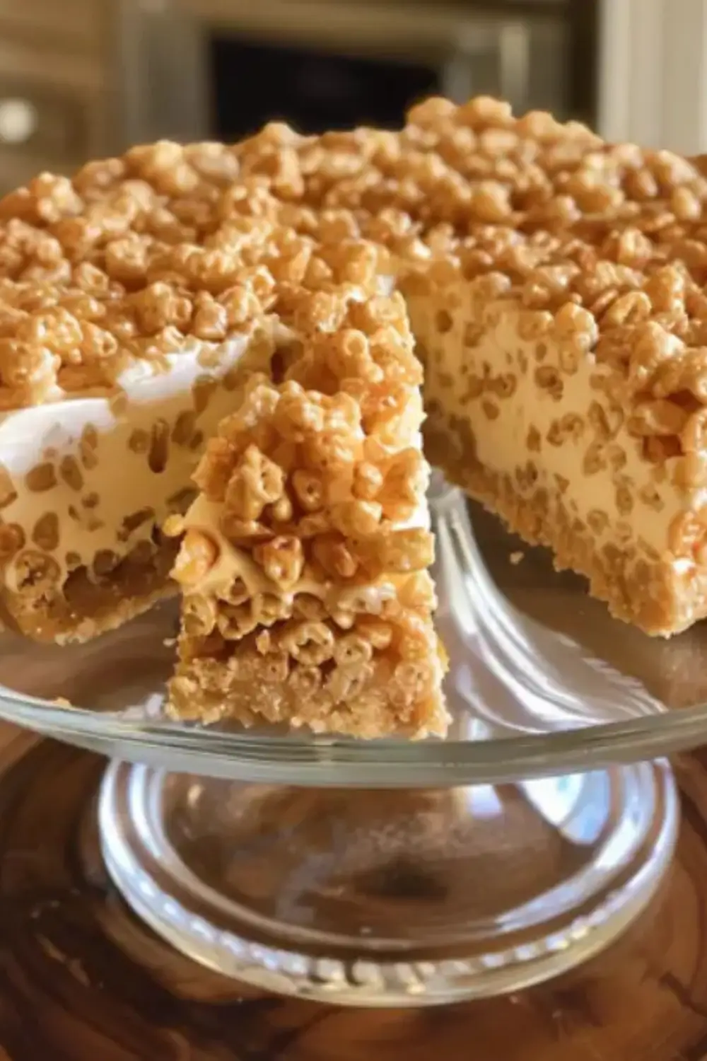 No-bake cheesecake with a crispy Rice Krispies crust, served on a glass cake stand with a slice cut out.