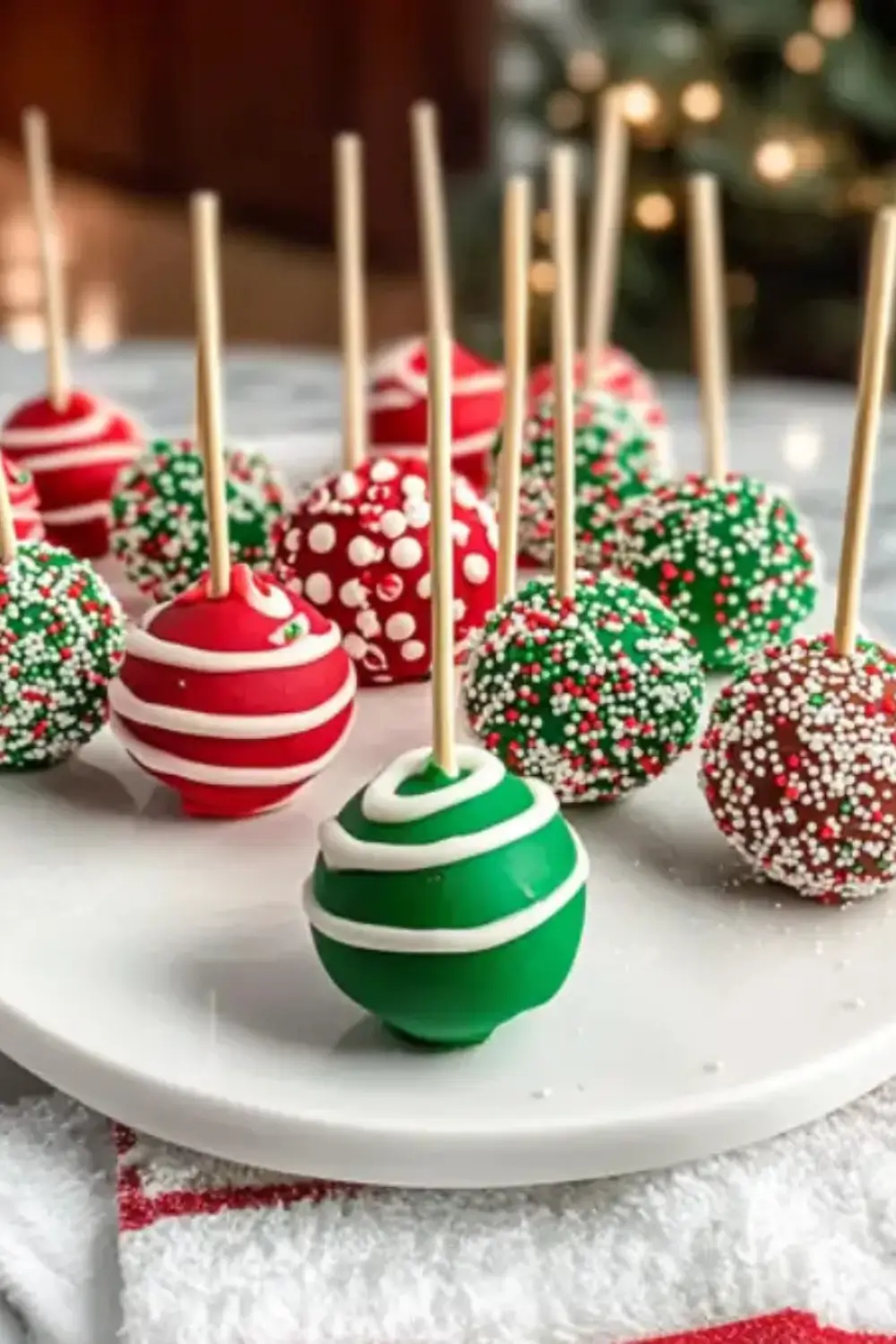 Colorful Christmas cake pops decorated with festive red, green, and white sprinkles and icing on sticks.