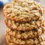 Stack of soft and chewy oatmeal cookies on a wooden surface.