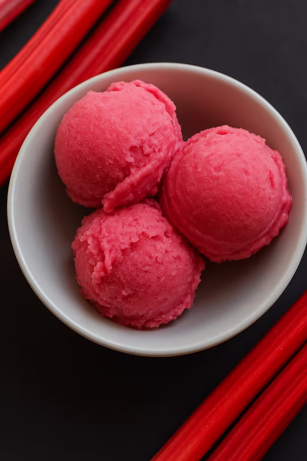 Bowl of vibrant pink rhubarb ice cream scoops