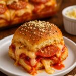 Close-up of a pepperoni pizza slider with melted cheese and marinara sauce, served on a white plate.