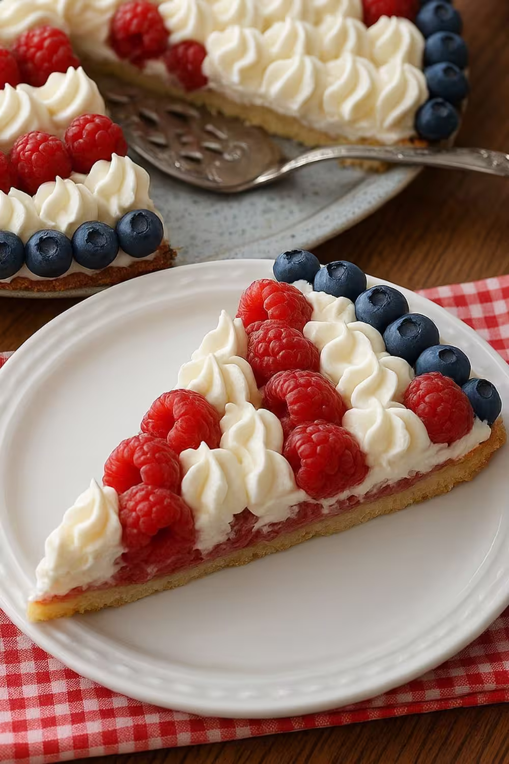 American Flag Fruit Pizza decorated with fresh raspberries, blueberries, and whipped cream in a patriotic pattern.