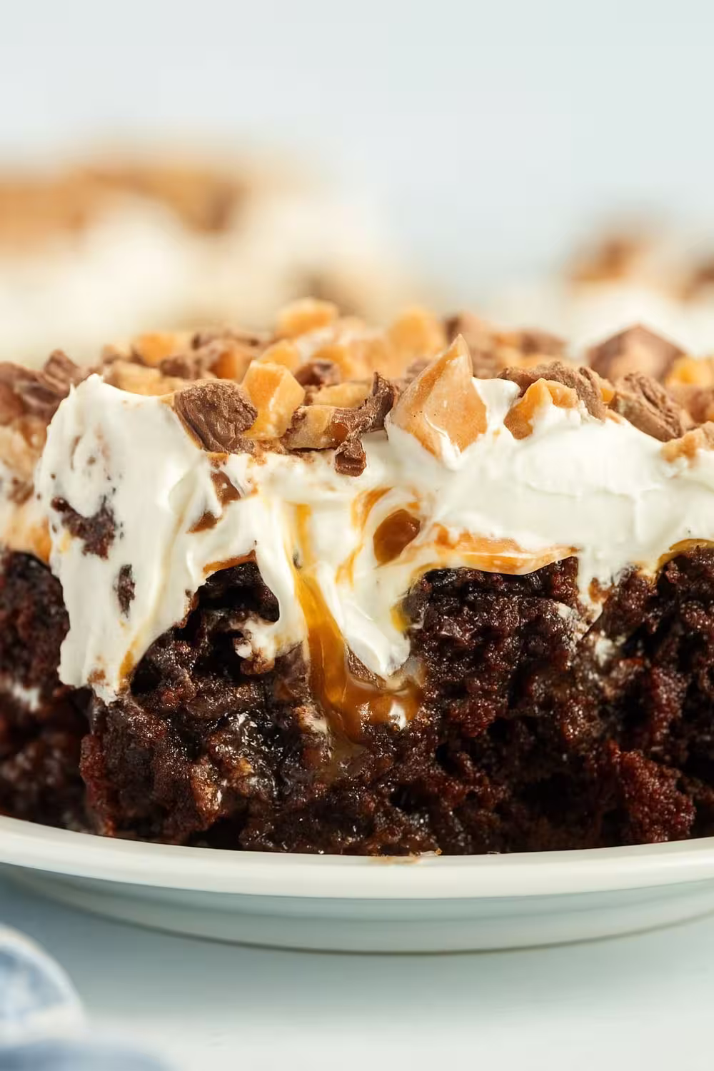 A close-up of Better Than Sex Cake showing layers of rich chocolate cake, caramel drizzle, whipped topping, and crushed toffee pieces.