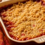 Golden-brown crumble topping over a bubbling strawberry and rhubarb filling, served in a rustic baking dish.