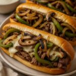 Easy Philly Cheesesteak Sandwiches with melted cheese, sautéed onions, peppers, and mushrooms on hoagie rolls.