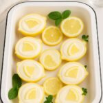 Creamy lemon posset served in lemon shells, garnished with lemon slices and mint leaves