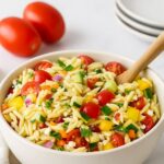 Fresh and colorful orzo salad recipe with cucumbers, cherry tomatoes, and bell peppers in a white bowl
