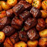 Tender garlic butter steak bites served with golden roasted potatoes in a cast iron skillet.