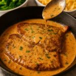 Juicy pan-seared steak smothered in a rich and creamy garlic sauce served in a cast iron skillet.
