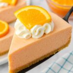 Jello Creamsicle Pie slice topped with whipped cream and a fresh orange wedge.