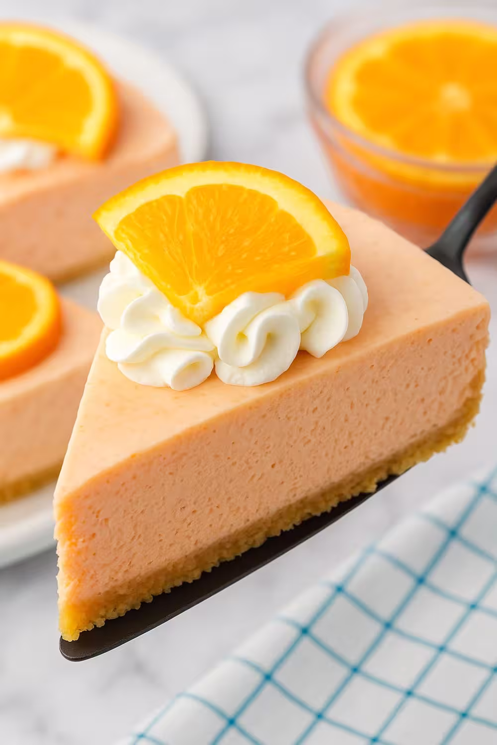 Jello Creamsicle Pie slice topped with whipped cream and a fresh orange wedge.