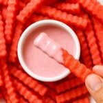 Crinkle-cut watermelon fries served with a creamy pink dipping sauce.