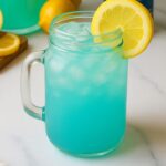 Mason jar filled with vibrant blue raspberry lemonade over ice, garnished with a lemon slice.