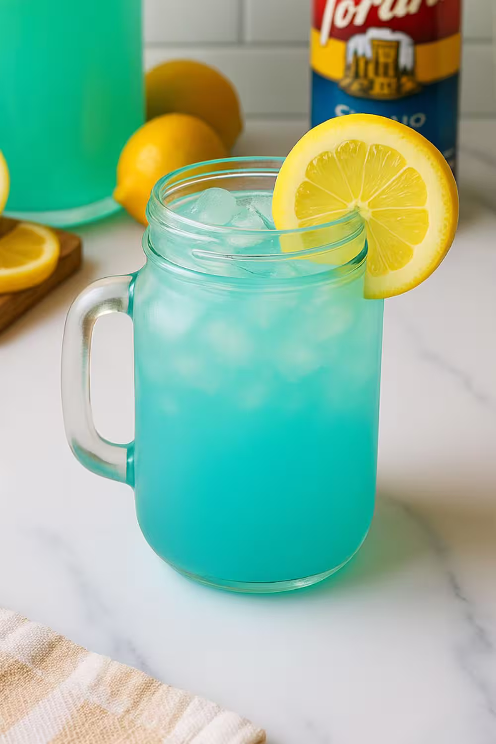 Mason jar filled with vibrant blue raspberry lemonade over ice, garnished with a lemon slice.