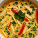 Bowl of Crockpot Thai Coconut Chicken Soup garnished with cilantro and red bell peppers