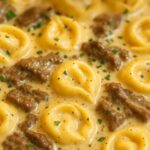 Cheesesteak tortellini simmered in a rich and creamy provolone sauce, garnished with herbs.