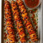 Grilled BBQ pineapple chicken kabobs served on metal skewers, garnished with fresh parsley, with a side of tangy barbecue sauce.