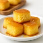 Golden honey butter cornbread poppers stacked on a white plate.