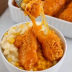 KFC Bowls A cheesy chicken tender being lifted from a bowl of creamy mashed potatoes and corn with a fork.