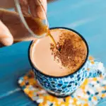 A hand pouring coffee into a mug on a blue table, illustrating the concept of a coffee loophole.
