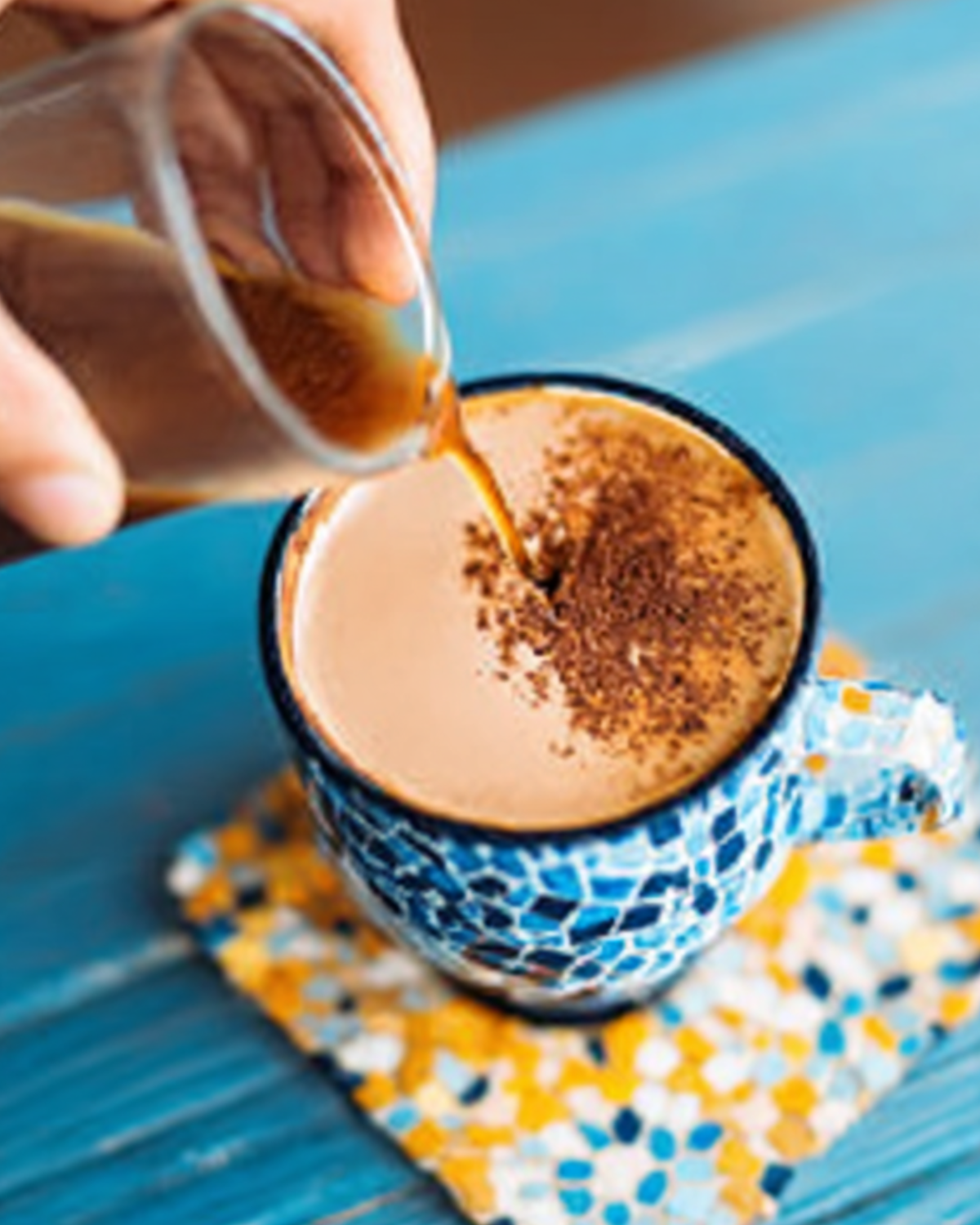 A hand pouring coffee into a mug on a blue table, illustrating the concept of a coffee loophole.