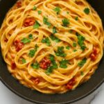 Creamy Sun-Dried Tomato Pasta garnished with fresh parsley in a skillet