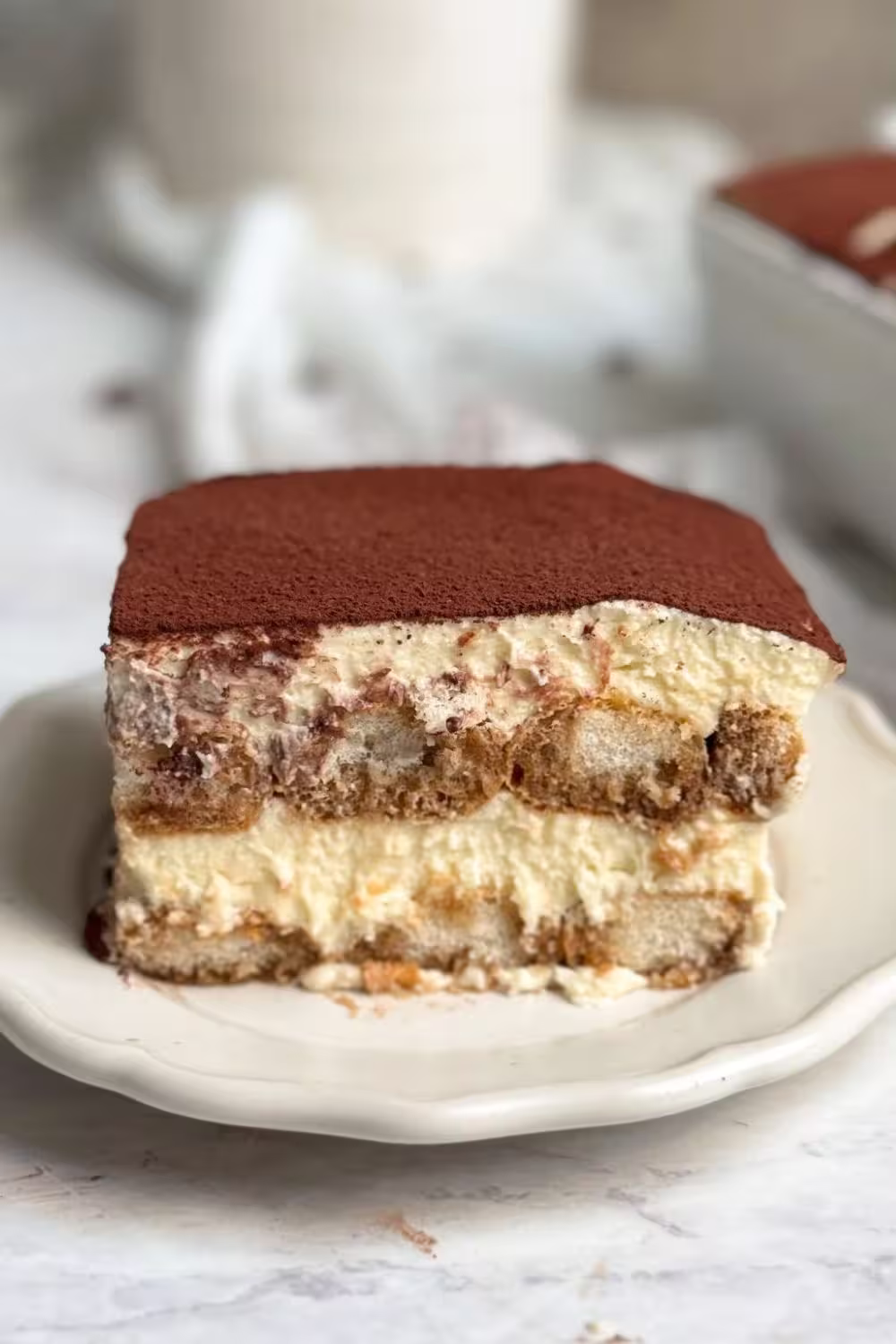 Close-up of a slice of Classic Italian Tiramisu with rich mascarpone layers and cocoa topping.