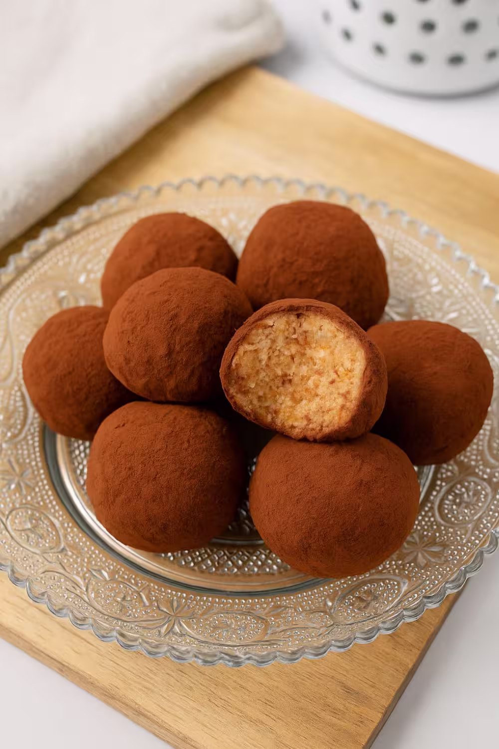 Homemade tiramisu truffles dusted in cocoa powder on a glass plate.