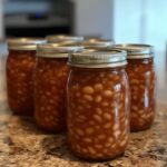 Jars of Canned Better Than Bush’s Baked Beans arranged on a kitchen counter.