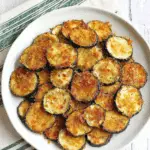 Plate of crispy baked zucchini slices coated in golden breadcrumbs.