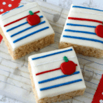 Notebook Paper Rice Krispies Treats decorated with white icing, blue and red lines, and small red apple designs.