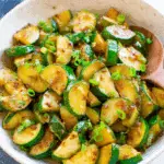 Bowl of sautéed zucchini slices garnished with chopped green onions.