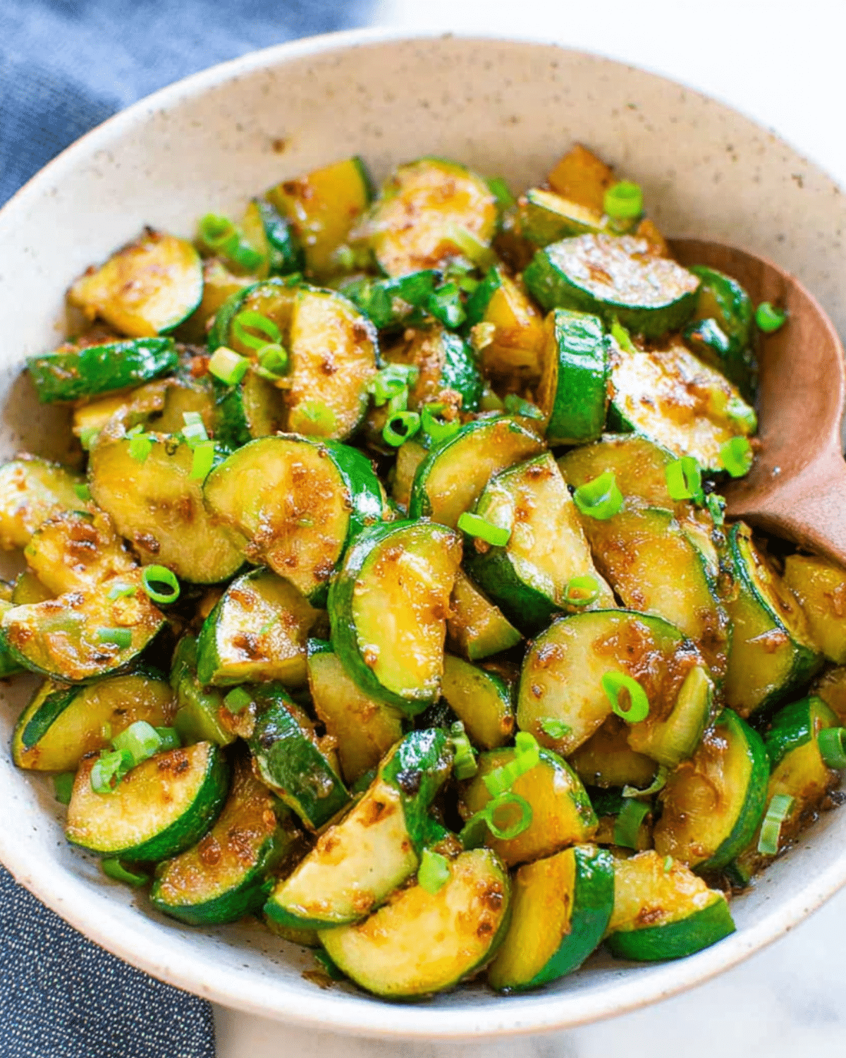Bowl of sautéed zucchini slices garnished with chopped green onions.