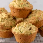 Freshly baked zucchini muffins stacked on a cooling rack.