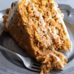 A moist slice of carrot cake Paula Deen pineapple style, layered with cream cheese frosting and filled with shredded carrots and pineapple chunks.