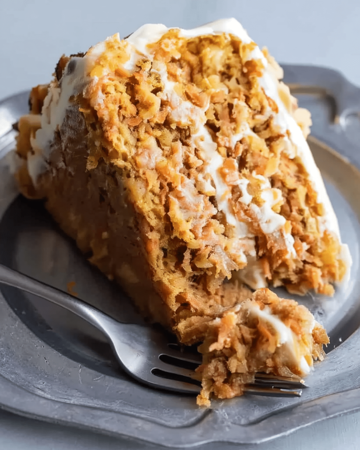 A moist slice of carrot cake Paula Deen pineapple style, layered with cream cheese frosting and filled with shredded carrots and pineapple chunks.