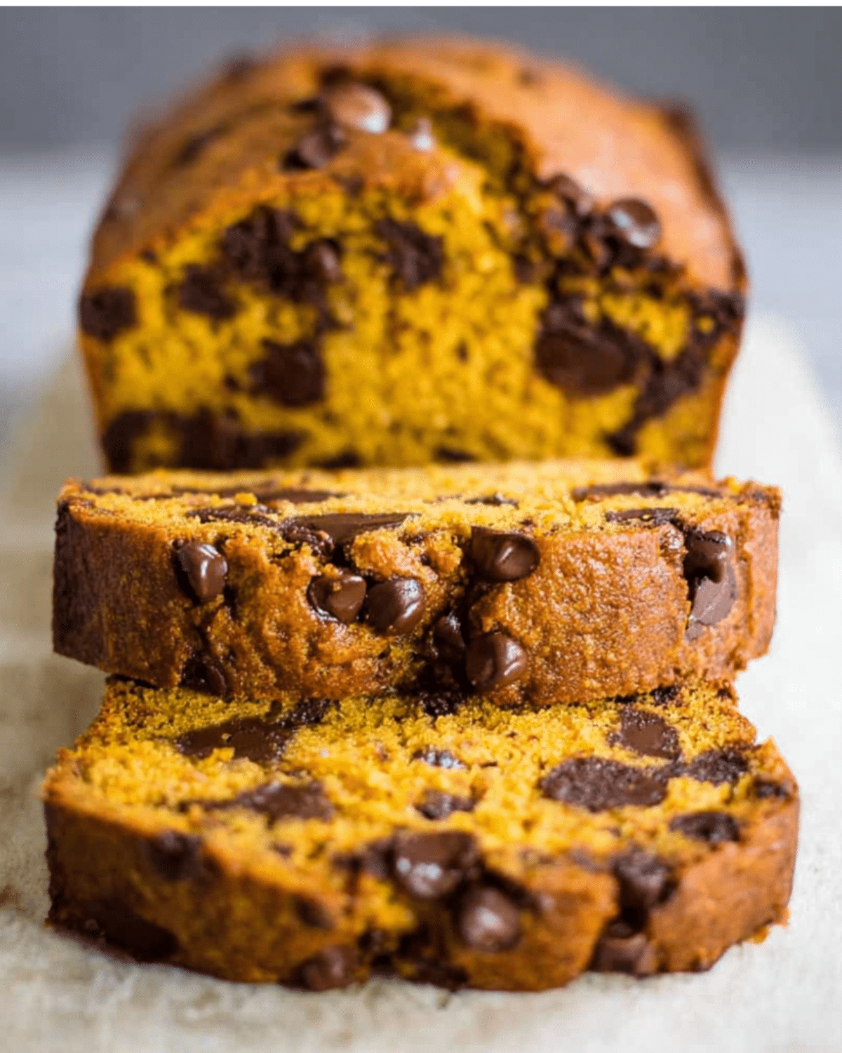 Slices of the best chocolate chip pumpkin bread filled with gooey chocolate chips and moist pumpkin crumb.